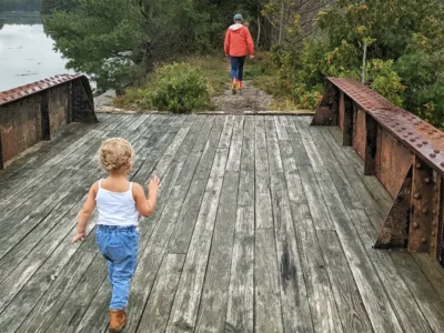 parent and child walking on old pond railway trail